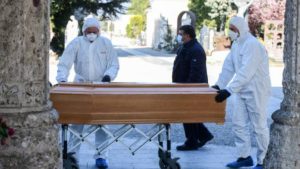 Undertakers wearing a face mask and overalls unload a coffin out of a hearse on March 16, 2020 at the Monumental cemetery of Bergamo, Lombardy, as burials of people who died of the new coronavirus are being conducted at the rythm of one every half hour. (Photo by Piero Cruciatti / AFP)